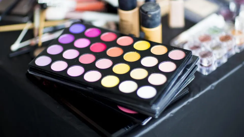 Bunte Lidschatten-Palette zwischen Foundation-Flaschen auf einem Schminktisch