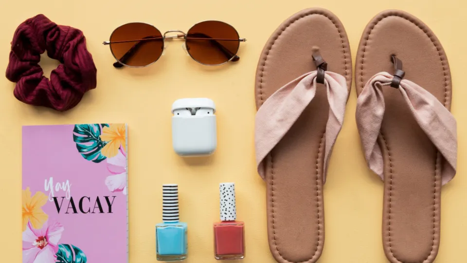 Flatlay mit Nagellacken, Haargummi und Notizheft auf gelbem Grund
