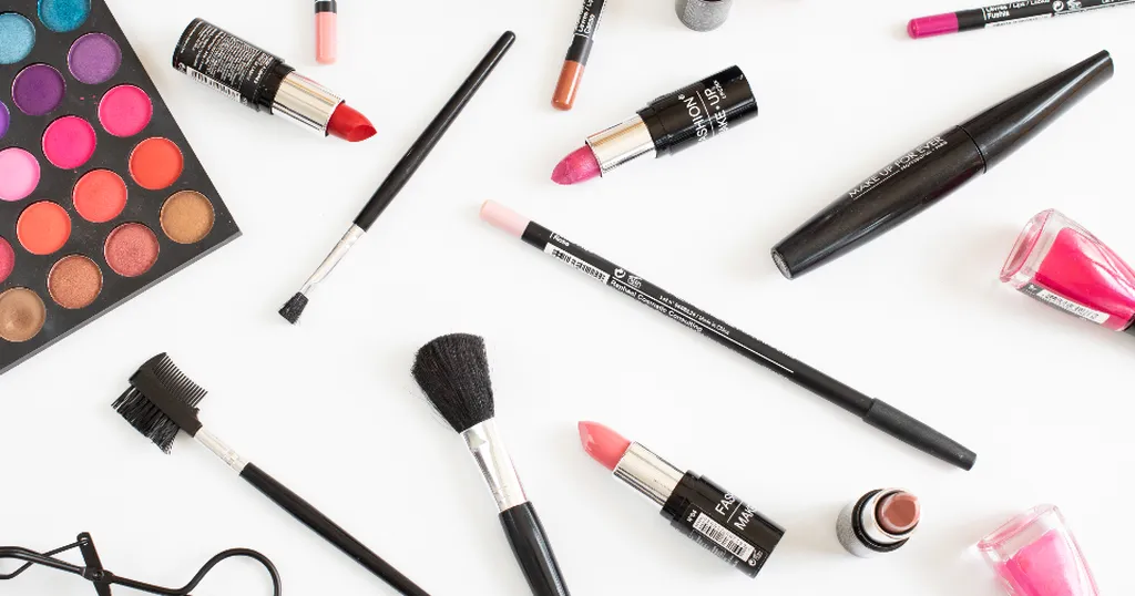 Lippenstifte, Pinsel und Lidschatten-Palette auf weißem Grund